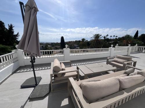 a patio with chairs and an umbrella on a balcony at Palacio Suites Marbella in Marbella
