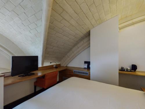 a room with a bed and a tv and a desk at Mercure Poitiers Centre in Poitiers