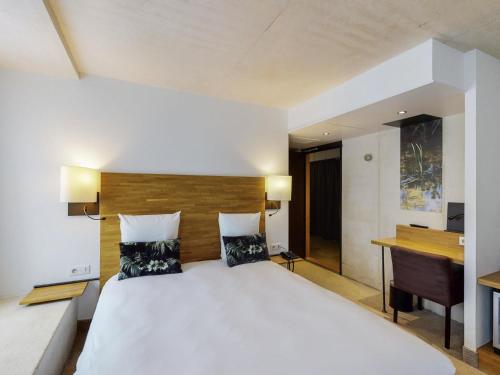 a bedroom with a large white bed and a desk at Mercure Poitiers Centre in Poitiers