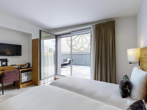 a hotel room with a bed and a balcony at Mercure Poitiers Centre in Poitiers