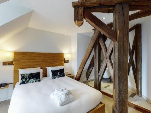 a bedroom with a large white bed with wooden beams at Mercure Poitiers Centre in Poitiers