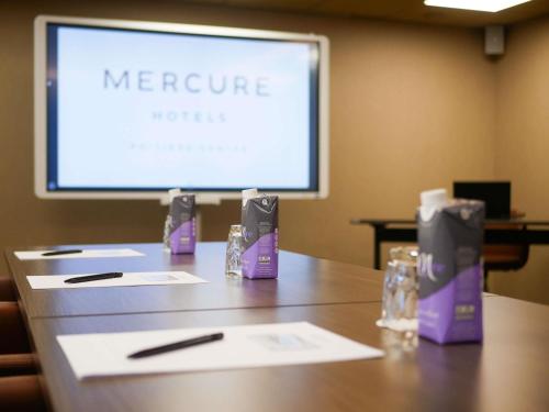 a table in a conference room with a screen at Mercure Poitiers Centre in Poitiers