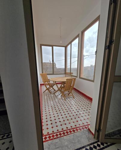 une table et des chaises dans une pièce avec des fenêtres dans l'établissement Riad Gogo, à Aït Ben Haddou