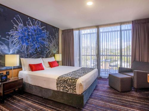a hotel room with a large bed and a chair at Mantra Gladstone in Gladstone