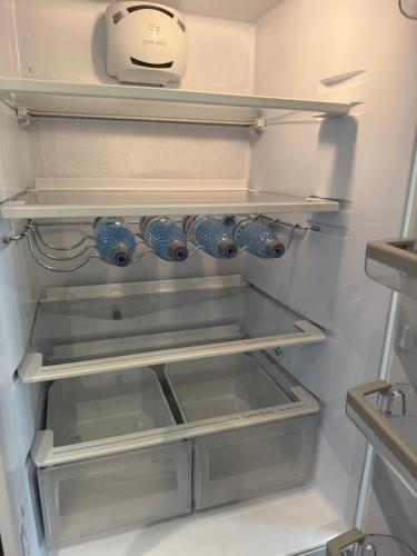 an open refrigerator with blue cups on the shelves at Apartament Casa Bella in Craiova