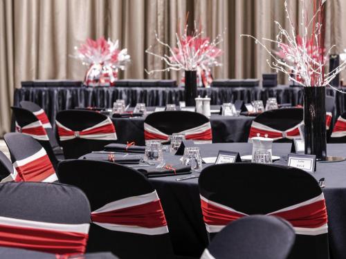 a row of tables with black and red chairs at Mantra Gladstone in Gladstone