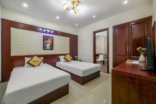 a hotel room with two beds and a television at Sunview Beach Hotel Danang in Da Nang
