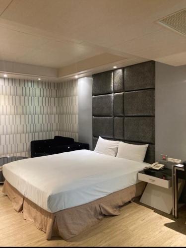a bedroom with a large white bed with a black headboard at Fairy Tale City Motel in Hualien City
