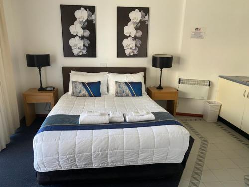 a bedroom with a large bed with pillows and two lamps at The Esplanade Motel in Lakes Entrance