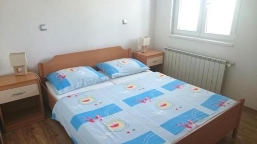 a bedroom with a bed with a blue comforter and pillows at Apartment Jure in Primošten