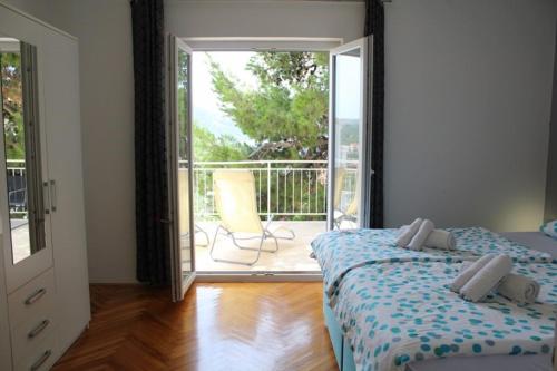 a bedroom with a bed and a balcony with a chair at Apartment Nana in Primošten