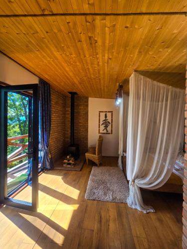 a living room with a wooden ceiling and a window at Villa Vejini cabin in Mamkoda