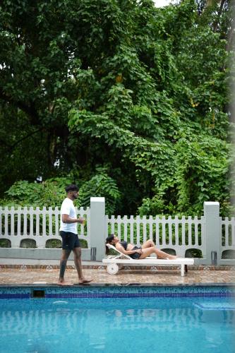 a man walking past a woman laying on a bench next to a pool at Hotel Lotus in Candolim