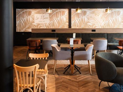 a restaurant with chairs and a table and a wall at Mercure Valenciennes Centre in Valenciennes
