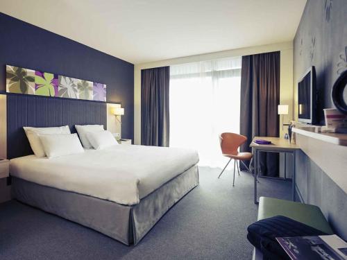 a hotel room with a large bed and a chair at Mercure Valenciennes Centre in Valenciennes