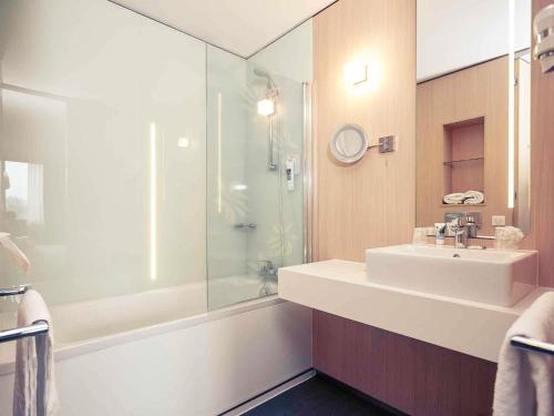 a bathroom with a sink and a glass shower at Mercure Valenciennes Centre in Valenciennes