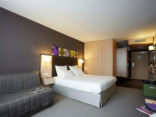 a hotel room with a bed and a couch at Mercure Valenciennes Centre in Valenciennes