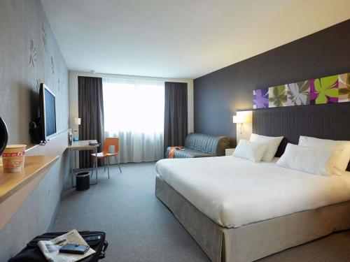 a hotel room with a large bed and a desk at Mercure Valenciennes Centre in Valenciennes