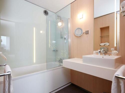 a bathroom with a white sink and a shower at Mercure Valenciennes Centre in Valenciennes