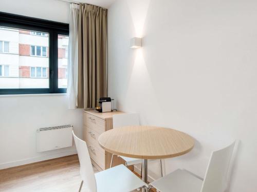 a room with a table and chairs and a window at Aparthotel Adagio Access Bruxelles Europe Aparthotel in Brussels