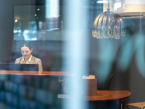 a man sitting at a table with a laptop at Mercure Wellington Central City Hotel and Apartments in Wellington
