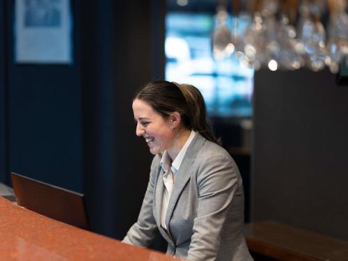 a woman sitting at a desk with a laptop at Mercure Wellington Central City Hotel and Apartments in Wellington
