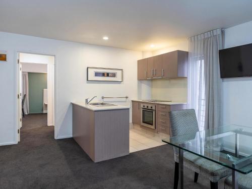 a kitchen and dining room with a glass table at Mercure Wellington Central City Hotel and Apartments in Wellington