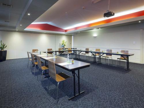 a conference room with long tables and chairs at ibis Styles Canberra in Canberra
