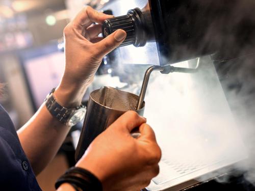 a person is holding a cup in a machine at ibis Styles Canberra in Canberra