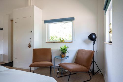 a bedroom with two chairs and a table and a window at De Heerlijkheid in Groenlo