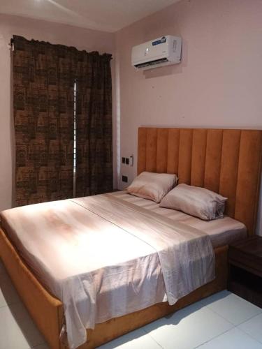 a bedroom with a large bed with a wooden headboard at Exclusive ANSO HOMES GRA Ikeja in Ikeja