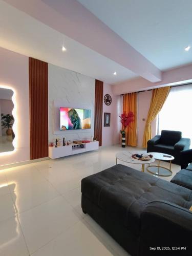 a large living room with a couch and a tv at Exclusive ANSO HOMES GRA Ikeja in Ikeja