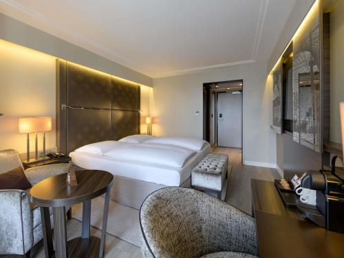 a hotel room with a bed and a table and chairs at Pullman Munich in Munich