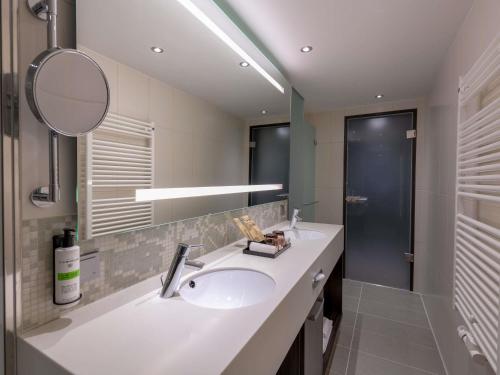 a bathroom with a sink and a mirror at Pullman Munich in Munich
