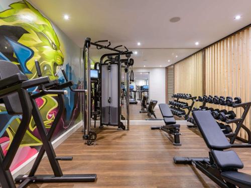 a gym with tread machines and a mural at Pullman Munich in Munich