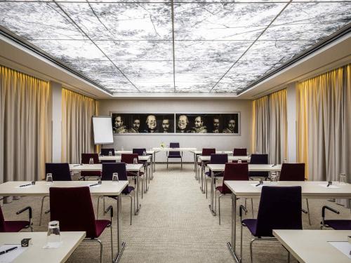 a dining room with tables and chairs and a ceiling at Pullman Munich in Munich