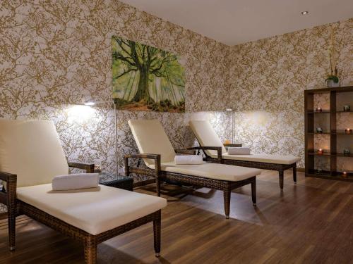a room with four chairs and a wall with wallpaper at Pullman Munich in Munich