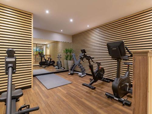 a gym with several treadmills and exercise bikes in a room at Pullman Munich in Munich