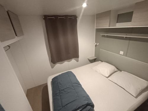 a small bedroom with a bed and a curtain at Mobil home prestations DELUXE 3ch climatisé avec Parc Aquatique in Canet-en-Roussillon