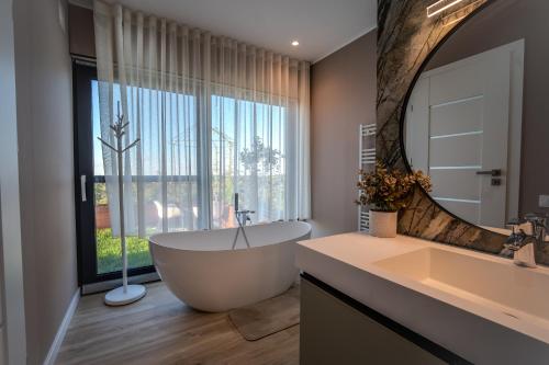 a bathroom with a large tub and a large mirror at Casa Deluxe in Sinteu - intersectia intre modern si linistea naturii in Şinteu