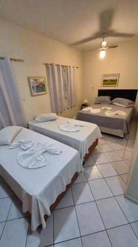 a room with three beds with white sheets at Vinte Park Hotel in Bragança Paulista