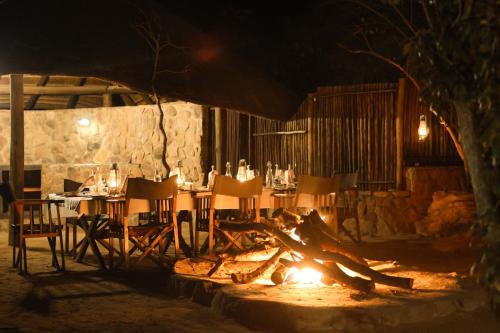 a table and chairs sitting next to a fire at Tshwene Lodge in Welgevonden Game Reserve