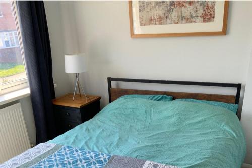 a bedroom with a bed with a blue comforter and a window at 3 bed semi detached house near Stourbridge in Stourbridge