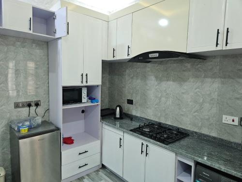 a kitchen with white cabinets and a stove top oven at Flat 1 Jonah Heights, Cluster 4, RiverParkEstate in Abuja