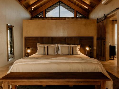 オチワロンゴにあるOtjiwa Savanna Luxury Villaの木製のヘッドボードが付いた大きなベッドのある寝室