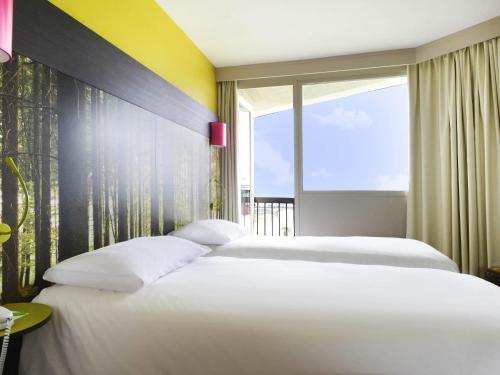 two white beds in a room with a window at ibis styles Dax Centre in Dax