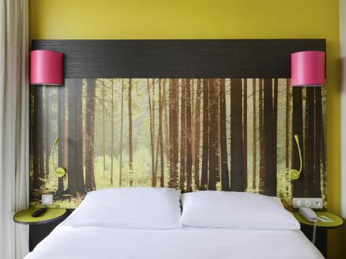 a bedroom with a bed with a forest backdrop at ibis styles Dax Centre in Dax