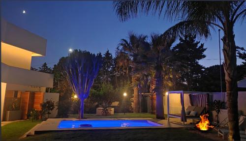 a backyard with a swimming pool at night at Shati Luxury - New, Heated Pool, Sea view Near beach in Fontane Bianche