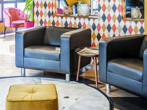 a room with two chairs and a couch and a table at Ibis Styles Reims Centre in Reims