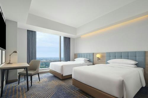 a hotel room with two beds and a desk at Four Points by Sheraton Bekasi in Bekasi